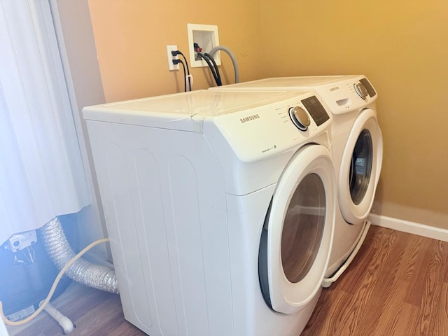 laundry room featuring separate washer and dryer, baseboards, laundry area, and wood finished floors