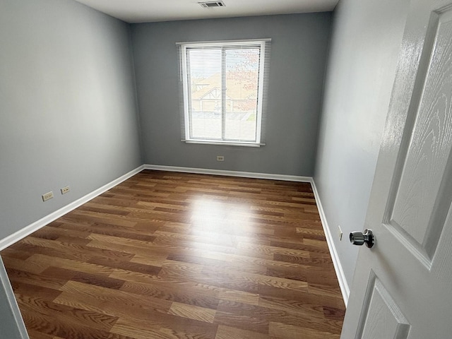 spare room featuring visible vents, dark wood finished floors, and baseboards