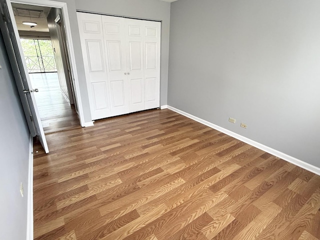 unfurnished bedroom featuring baseboards, wood finished floors, and a closet