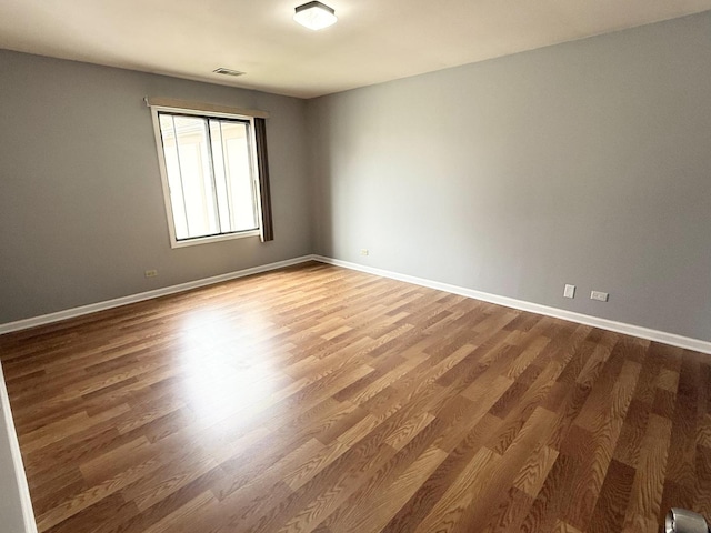 unfurnished room with baseboards, visible vents, and wood finished floors