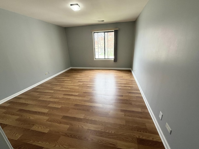 unfurnished room featuring visible vents, baseboards, and wood finished floors