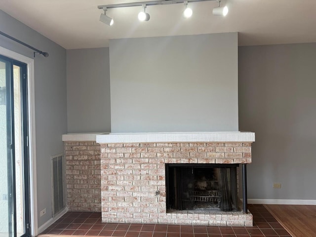 details featuring a brick fireplace, visible vents, and track lighting