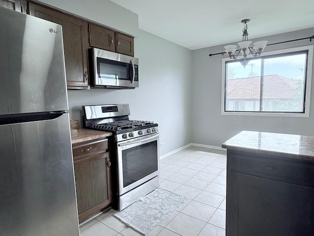 kitchen featuring light stone countertops, dark brown cabinets, a chandelier, stainless steel appliances, and light tile patterned flooring