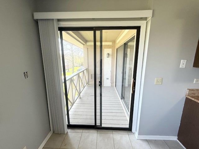 doorway featuring light tile patterned floors and baseboards