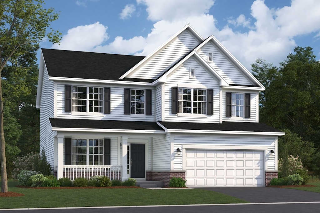 traditional-style house with a porch, an attached garage, driveway, and a front yard