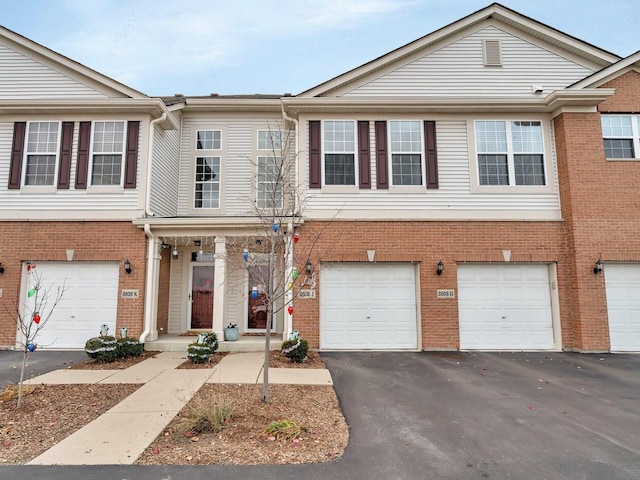 view of property featuring a garage, driveway, and brick siding
