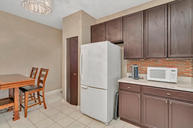 kitchen featuring light countertops, dark brown cabinetry, white appliances, and light tile patterned flooring