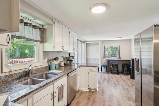 38622 N Drexel Blvd, Antioch, IL 60002 - kitchen featuring appliances with stainless steel finishes, a sink, dark stone countertops, light wood-style flooring, and white cabinetry