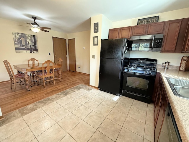 kitchen with black appliances, light wood-style floors, a ceiling fan, a sink, and light countertops