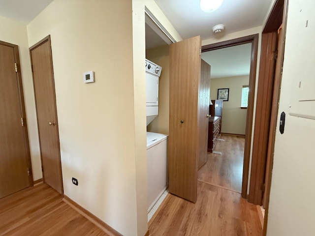 hall featuring stacked washer / dryer and light wood-type flooring
