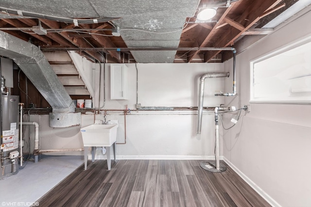 basement with baseboards, gas water heater, and wood finished floors