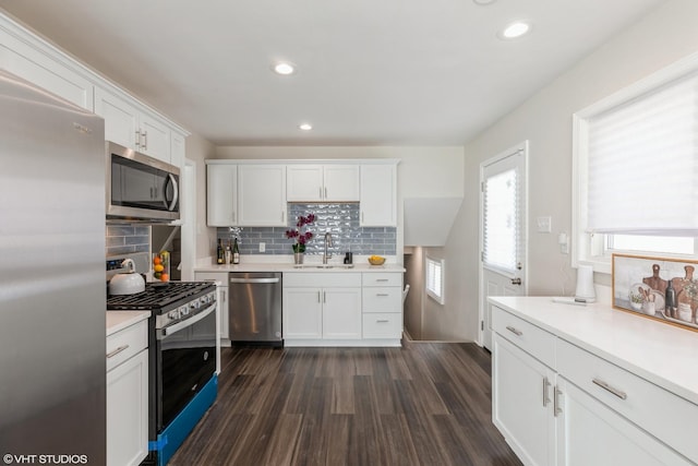 kitchen with dark wood-style flooring, a sink, light countertops, stainless steel appliances, and white cabinetry