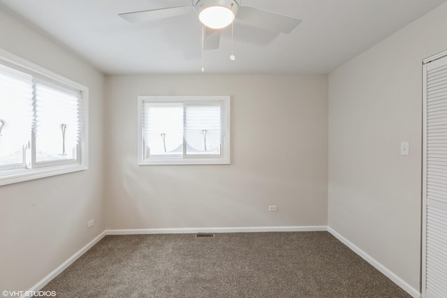 carpeted empty room with baseboards, a ceiling fan, and visible vents