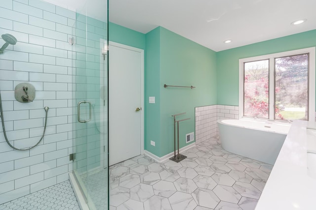bathroom featuring a shower stall, a soaking tub, tile patterned floors, recessed lighting, and a wainscoted wall