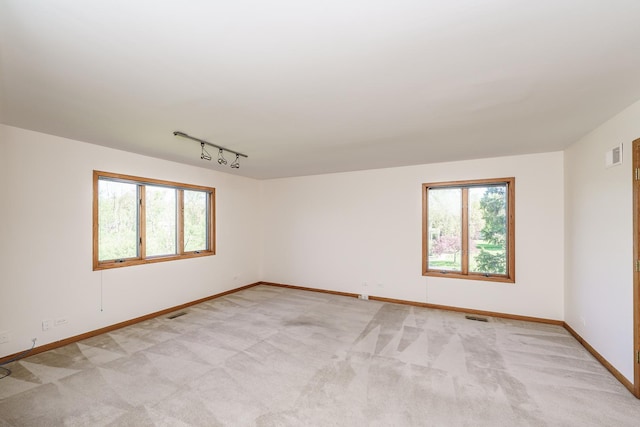 spare room featuring plenty of natural light, light carpet, and baseboards