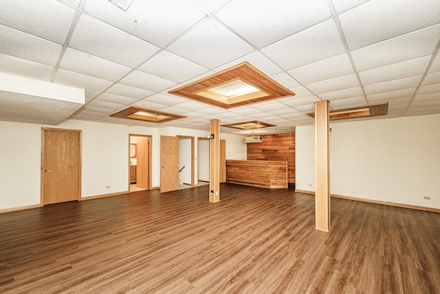 finished basement with a drop ceiling, wood finished floors, and baseboards