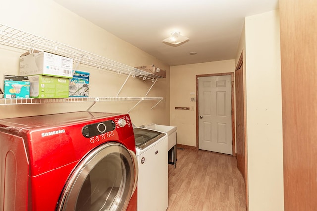 clothes washing area featuring independent washer and dryer and light wood-style floors
