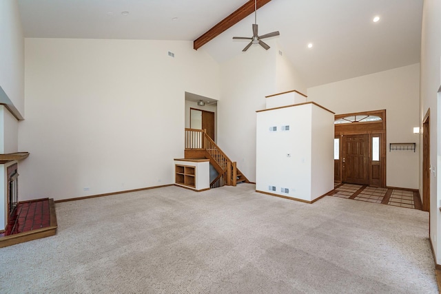 unfurnished living room with high vaulted ceiling, beam ceiling, carpet floors, a ceiling fan, and stairway