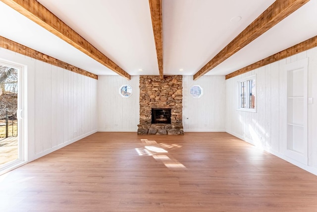 unfurnished living room with beamed ceiling, wood walls, wood finished floors, and a fireplace