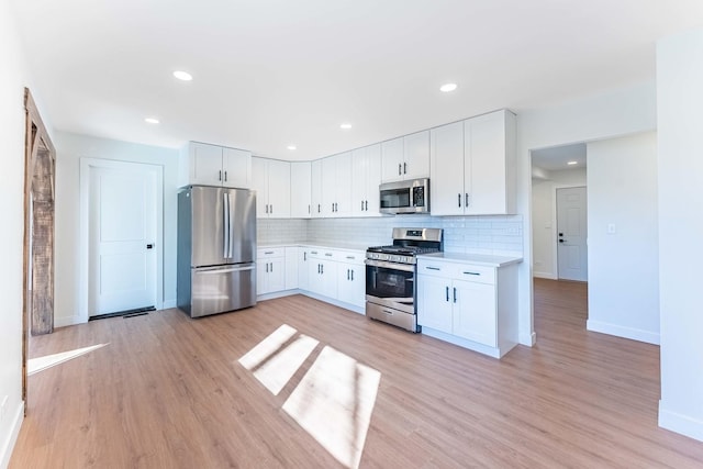 kitchen featuring light countertops, appliances with stainless steel finishes, decorative backsplash, and baseboards