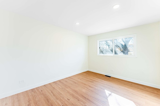 empty room with baseboards, visible vents, and wood finished floors