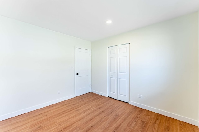 unfurnished bedroom featuring recessed lighting, baseboards, a closet, and light wood-type flooring