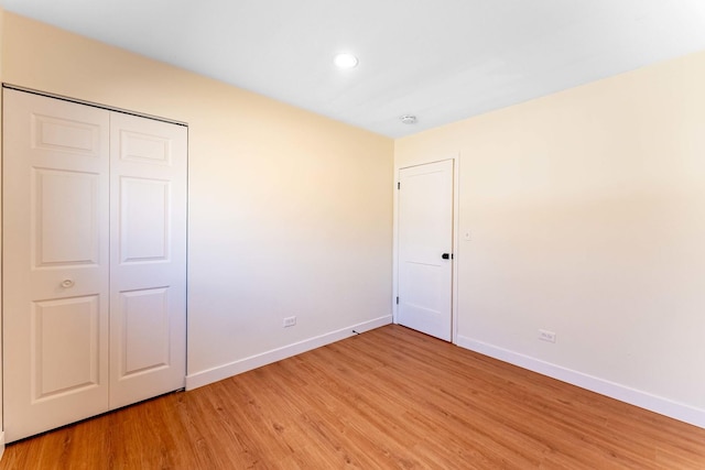 unfurnished bedroom with baseboards, recessed lighting, a closet, and light wood-type flooring