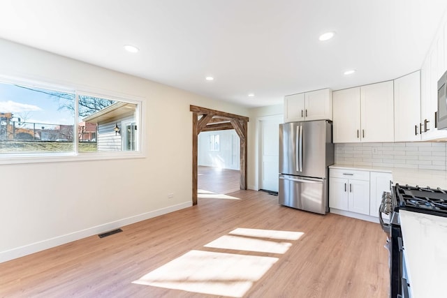 kitchen featuring visible vents, light wood-style floors, white cabinets, tasteful backsplash, and appliances with stainless steel finishes