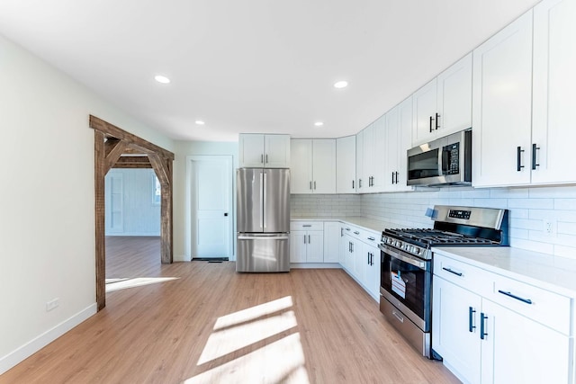 kitchen featuring light countertops, baseboards, backsplash, and stainless steel appliances