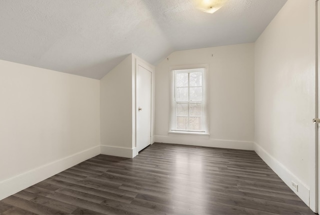 bonus room with baseboards, a textured ceiling, dark wood-style flooring, and vaulted ceiling