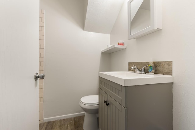 bathroom with vanity, baseboards, wood finished floors, and toilet