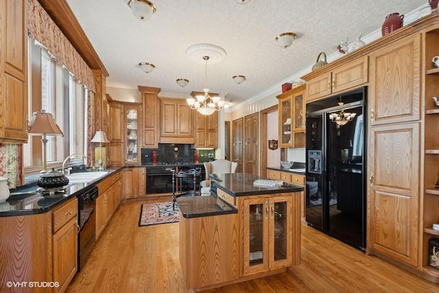 kitchen with crown molding, an inviting chandelier, a sink, a kitchen island, and black appliances