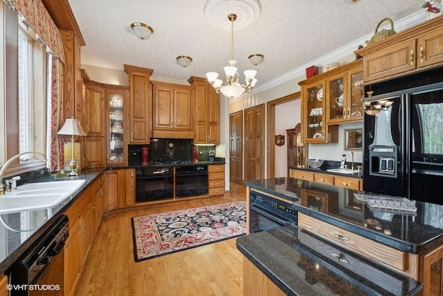 kitchen with brown cabinets, a notable chandelier, a sink, and black appliances