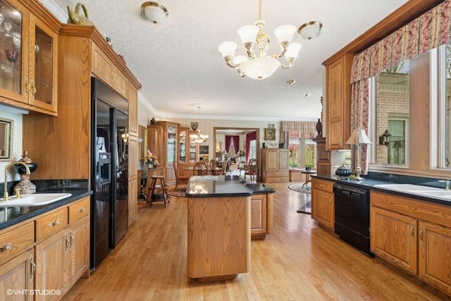 kitchen with a center island, dark countertops, a sink, black appliances, and an inviting chandelier