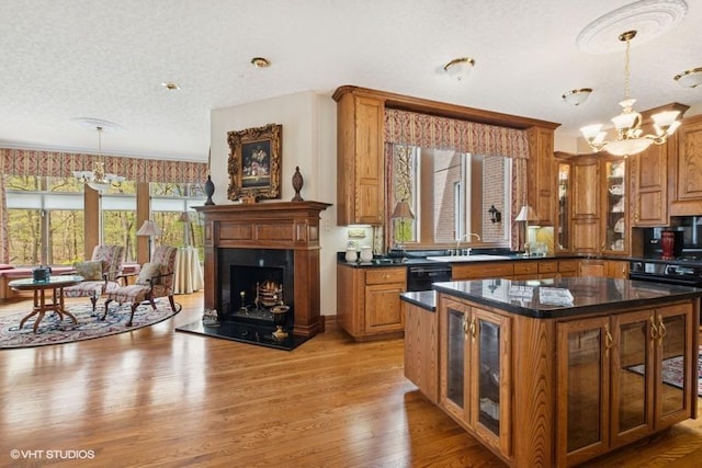 kitchen with glass insert cabinets, brown cabinets, a chandelier, light wood finished floors, and hanging light fixtures