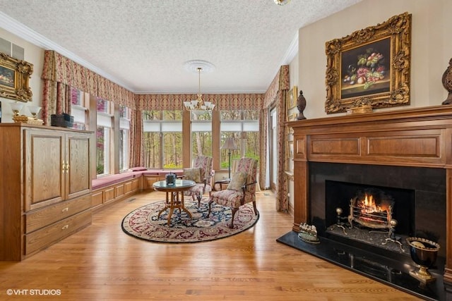 living area featuring a textured ceiling, a lit fireplace, ornamental molding, and light wood finished floors
