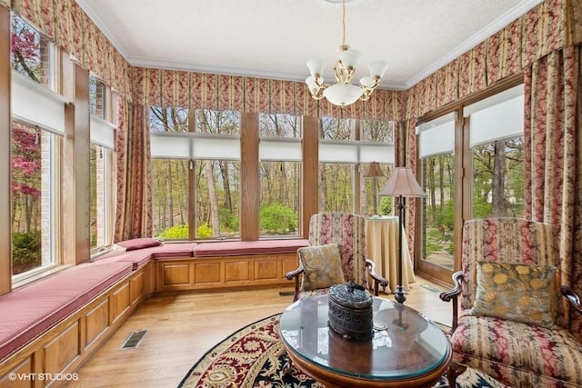 sunroom with a chandelier, visible vents, ornamental molding, and wood finished floors