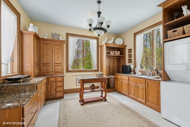 office area featuring stacked washer and dryer, a sink, light tile patterned floors, and a wealth of natural light