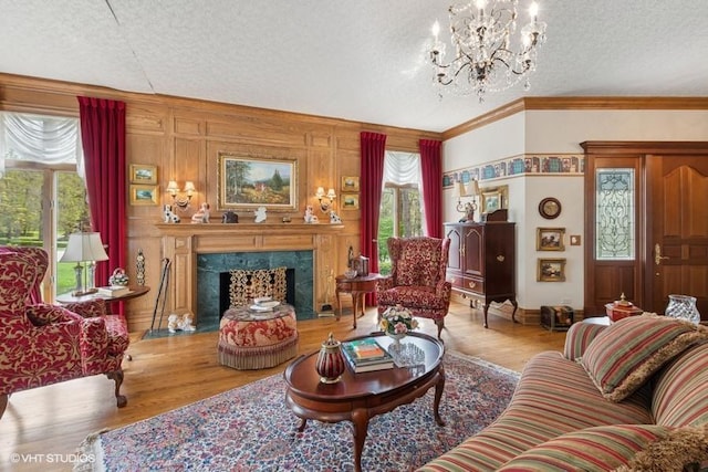 living room featuring an inviting chandelier, a textured ceiling, crown molding, and wood finished floors