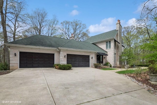 view of front of home with brick siding, a garage, driveway, and a chimney