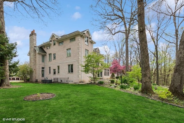 back of property featuring a lawn, brick siding, and a chimney