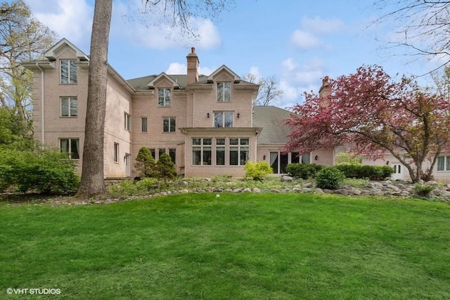 rear view of house featuring a lawn, brick siding, and a chimney