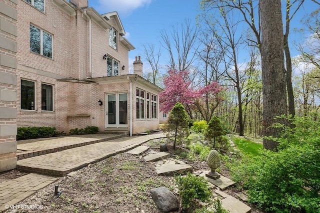rear view of house with a chimney, a patio area, and brick siding