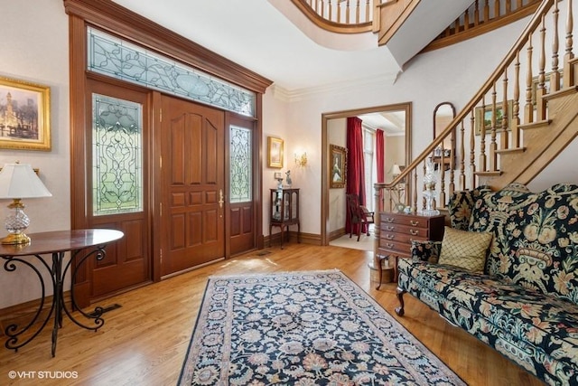 entryway featuring crown molding, baseboards, stairway, and wood finished floors