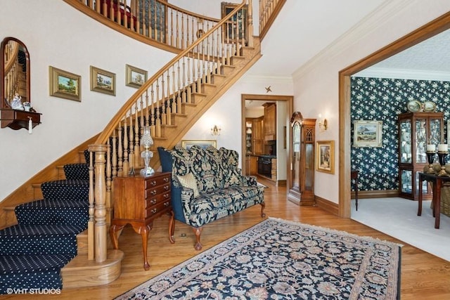 interior space with baseboards, wallpapered walls, ornamental molding, and wood finished floors
