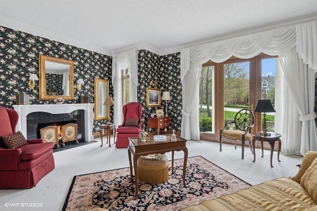 living area with carpet flooring, crown molding, a tiled fireplace, and wallpapered walls