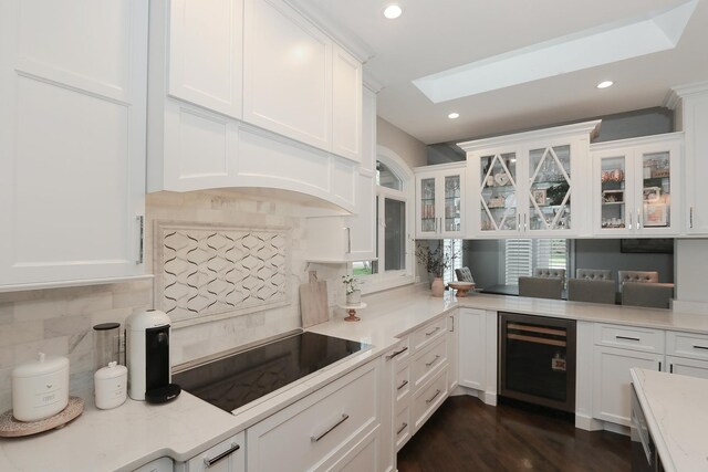 67 Katrina Ln, Sleepy Hollow, IL 60118 - kitchen with wine cooler, black electric stovetop, a skylight, tasteful backsplash, and white cabinetry