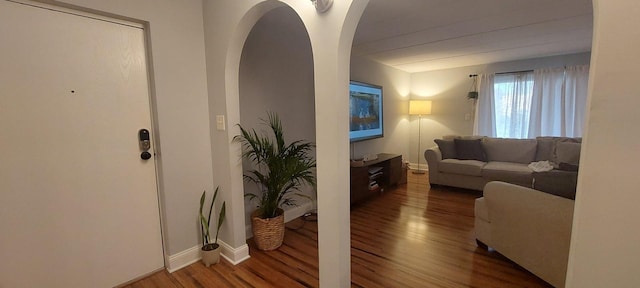 living area featuring baseboards, arched walkways, and wood finished floors
