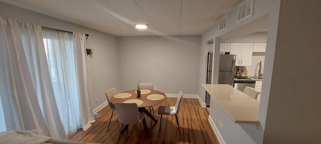 dining room featuring visible vents, baseboards, and wood finished floors