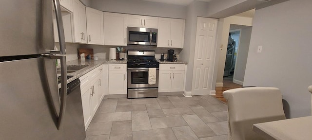kitchen featuring white cabinets, light stone countertops, and stainless steel appliances